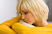 Close-up of a young woman hugging a cushion and thinking