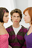 Close-up of a teenage boy standing with two young women