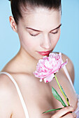 Young woman smelling peony