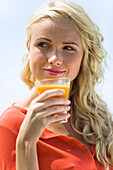 Portrait of a young  blond woman holding a fruit juice glass