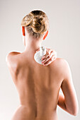 Woman massaging her shoulder with a herbal pack