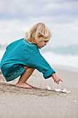 Girl playing with shells on the beach