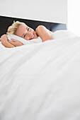 Woman hugging a pillow on the bed