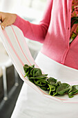 Woman holding spinach leaves in the kitchen