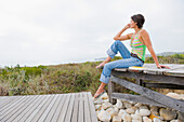 Woman sitting on a boardwalk and thinking