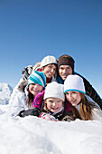 Happy family lying in snow, smiling at camera