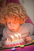 Boy blowing out candles on his birthday cake