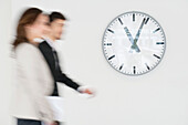 Business executives walking together in front of a wall clock