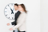 Business executives walking together in front of a wall clock