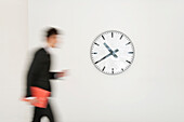 Businessman walking in front of a clock