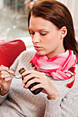 Young woman taking cough medicine