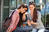 Two female friends reading text message on a mobile phone