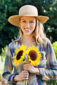 Portrait of a young woman holding sunflowers in a field