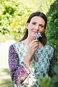 Portrait of a smiling mature woman smelling flowers in garden