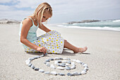 Girl arranging pebbles in spiral shape on the beach
