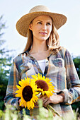Young woman holding sunflowers in a field