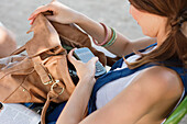 Woman checking her mobile in a purse, Paris, Ile-de-France, France