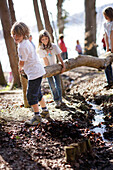 Kinder toben am Seeufer und tragen einen Baumstamm, Schlosspark Leoni, Leoni, Berg, Starnberger See, Bayern Deutschland