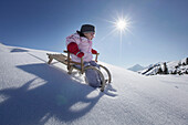 Two year old girl on a sledge, Kloesterle, Arlberg, Tyrol, Austria