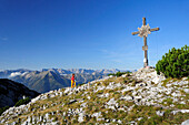 Woman walking towards cross at summit, Unnuetz, Unnutze, Rofan mountain range, Brandenberg Alps, Tyrol, Austria