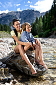 Eien Frau und ein Junge sitzen auf einem Fels am Fluss, Südtirol, Italien, Europa