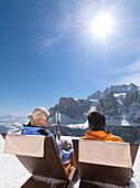 Ein Paar auf Liegestühlen in verschneiter Berglandschaft, Alto Adige, Südtirol, Italien, Europa