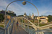 Woman cycling over Mozartsteg bridge, Salzburg, Austria