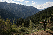 Backpacker with outstretched arms looks over a Himalayan scene, Laya, North West Bhutan