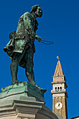 Statue of the local composer and violinist Giuseppe Tartini (1692-1770) and the clock tower of St. George's Cathedral, Piran, Slovenia.