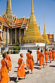 Young monks at Wat Phra Kaeo walking towards Royal Pantheon, Bangkok, Thailand