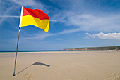 Yellow and red flag on the beach at Sennen Cove, Cornwall, England