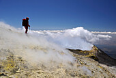Italy, Sicily,  Etna volcano, woman standing at the top of the main crater in smokes and gas