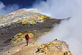 Italy, Sicily, Etna volcano woman walking on the top of the main crater, smokes, gas and sulfur