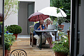 Couple working on terrace under the rain