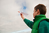 Boy playing with paper airplane at seaside