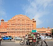Two men pushing loaded rickshaw in front of palace of winds, palace of winds, Hawa Mahal, Jaipur, Rajasthan, India