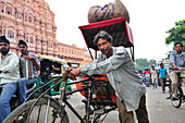 Man pushing loaded rickshaw in front of palace of winds, palace of winds, Hawa Mahal, Jaipur, Rajasthan, India