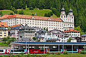 Benedictine monastery Disentis Abbey in the village of Disentis with train station and Glacier Express, Surselva, Graubuenden, Switzerland