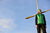 Junge Frau steht bei einem Gipfelkreuz in den Bergen, See, Tirol, Österreich