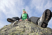 Junge Frau sitzt auf einem Felsen in den Bergen, See, Tirol, Österreich