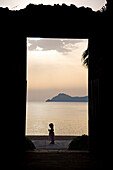 View through a doorway at the silhouette of a little girl on Lopud island, Elafti Islands, Croatia.