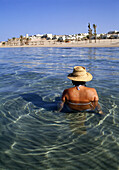 Woman wearing a sun hat wading in the Red Sea, Red Sea Coast, Egypt