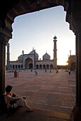 Tourist looking over the main courtyard of the Jami Masjid at dusk, Delhi, India