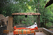 Woman reclining on chaise lounge on a patio in the jungle, Bandhavgarh, Madhya Pradesh, India