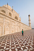 Woman walking beneath the Taj Mahal on tiled ground, Agra, Uttar Pradesh, India
