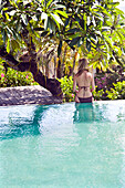Young woman by hotel swimming pool, Balangan, Bali, Indonesia