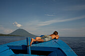 Man sunbathing on boat, Manado Tua, North Sulawesi