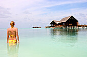 Woman in bikini near huts on stilts, Maldives