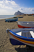 Painted fishing boats on beach and Rock of Gibraltar, La Linea, Costa del Sol, Spain