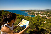 Girl checking map, with views of Llafranc and Calella beaches from San Sebastian lighthouse, Costa Brava, Catalunya, Spain